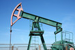 green oil well pump under blue sky