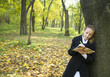 Teen girl writes a poetry in autumn park Teen girl writes a poetry in autumn park