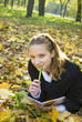 Teen girl lies in autumn park with her diary