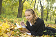 Teen girl lies in autumn park with her diary