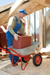 Builder roofer and wheel barrow with clay tile