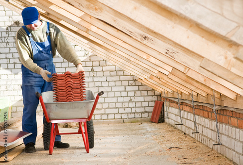 Photo: Builder roofer and wheel barrow with clay tile Builder roofer and wheel barrow with clay tile
