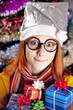Funny girl in christmas cap with gift boxes