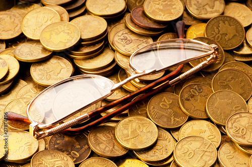 Photo: Many coins and reading glasses as business concept Many coins and reading glasses as business concept