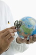 Doctor's hands holding stethoscope to globe
