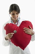 Doctor with stethoscope on heart pillow