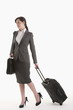 Young woman in suit with wheeled suitcase