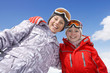 Smiling brother and sister in cap and goggles hugging