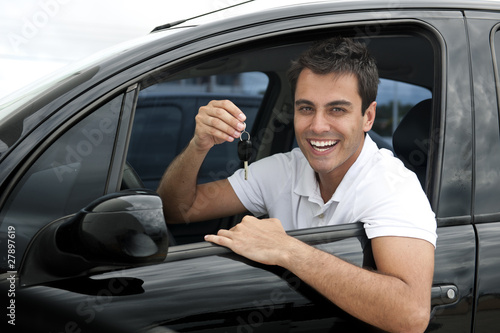 Photo: Happy hispanic man in his new car showing key Happy hispanic man in his new car showing key