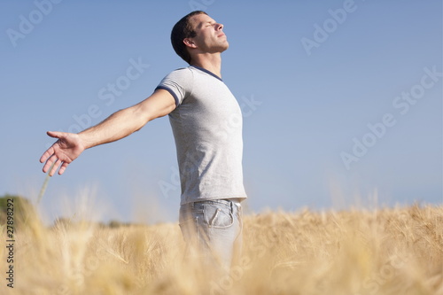 Foto: Man looking up with arms stretched out in wheat field Man looking up with arms stretched out in wheat field