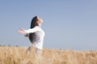 Woman with arms stretched out in wheat field