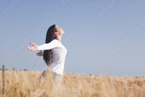 Photo: Woman with arms stretched out in wheat field Woman with arms stretched out in wheat field