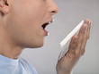 Close-up of mid adult man coughing into tissue, studio shot
