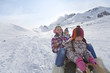 Mother and children sledding down mountain on winter day