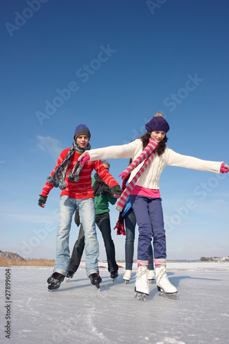 Photo: Family ice-skating on frozen lake together Family ice-skating on frozen lake together