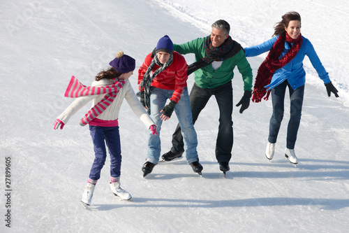 Photo: Family ice-skating on frozen lake together Family ice-skating on frozen lake together