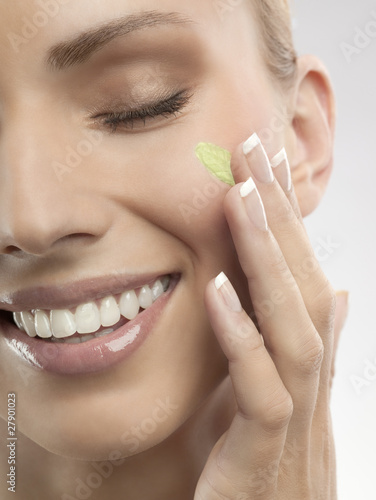 Photo: A woman putting green cream on her face A woman putting green cream on her face