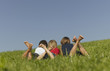 Three children lying in the grass together, view from behind