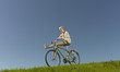 A woman freewheeling downhill on a bicycle in summertime