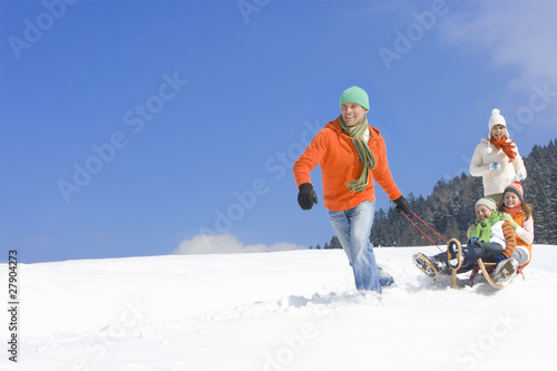 Photo: Father pulling children on sled downhill on ski slope Father pulling children on sled downhill on ski slope