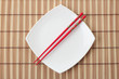 Red chopsticks and white dish on a bamboo napkin