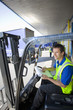 Worker in forklift writing on clipboard on loading dock