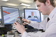 CAD designer measuring part at desk in office