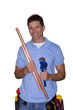 Smiling plumber holding copper pipe and wrench