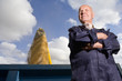 Senior farmer standing with crops filling bin behind him