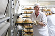 Baker removing fresh loaves of bread from oven