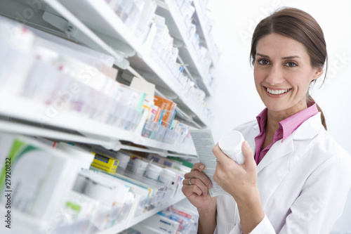 Photo: Pharmacist reading medicine bottle in pharmacy Pharmacist reading medicine bottle in pharmacy