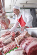 Smiling butcher arranging meat in display case