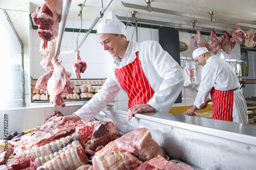 Foto: Smiling butcher arranging meat in display case Smiling butcher arranging meat in display case