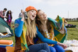 Young women wrapped in blanket and listening to radio at outdoor festival