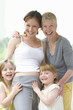 Grandmother standing and smiling with granddaughters and pregnant daughter