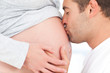 Close up of a man kissing the belly of his lovely pregnant wife