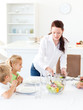 Adorable mother serving salad to her children for lunch