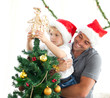 Father helping his son to put an angel on the Christmas tree