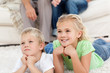 Brother and sister watching television on the floor with their p