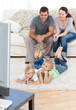 Adorable siblings watching television with their parents lying o