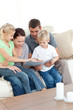 Happy family looking at a photo album sitting together in the li