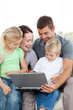 Adorable family working together on a laptop sitting on the sofa