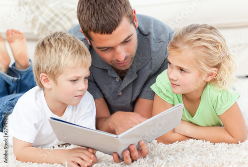 Photo: Children with father reading book in the carpet Children with father reading book in the carpet