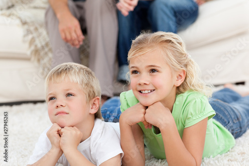Photo: Brother and sister watching television on the floor with their p Brother and sister watching television on the floor with their p