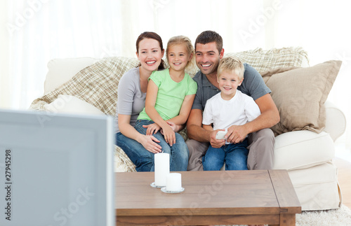 Photo: Adorable family watching television together sitting on the sofa Adorable family watching television together sitting on the sofa