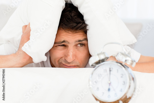 Photo: Handsome man putting his head under the pillow Handsome man putting his head under the pillow