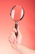 Magnifying glass in woman hand  on red background