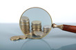 Closeup view of a magnifying glass looking at a stack of coins