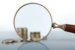 Closeup view of a magnifying glass looking at a stack of coins