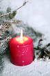 candela rossa con rami di pino innevati candela rossa con rami di pino innevati